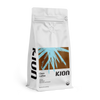 Kion Clean Coffee Ground Dark Roast in a white, resealable 12 oz coffee bag with a one-way freshness valve. The front features a blue botanical graphic over a brown background, the Kion logo, USDA Organic seal, and text reading "Rich, Bold, and Smooth." The bag is shown at a slight angle on a black background.