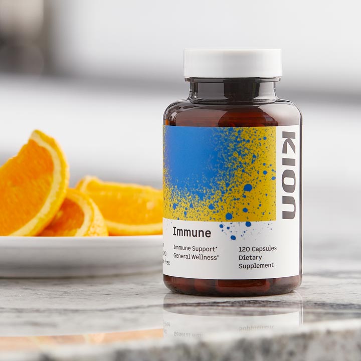 Supplement bottle labeled 'Immune' with oranges on a marble surface
