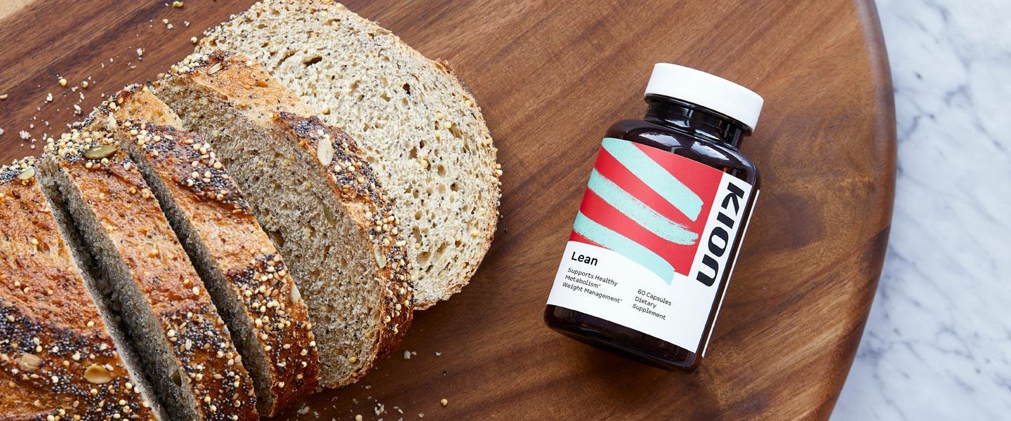 A bottle of KION Lean supplement placed on a wooden cutting board next to sliced artisanal bread.